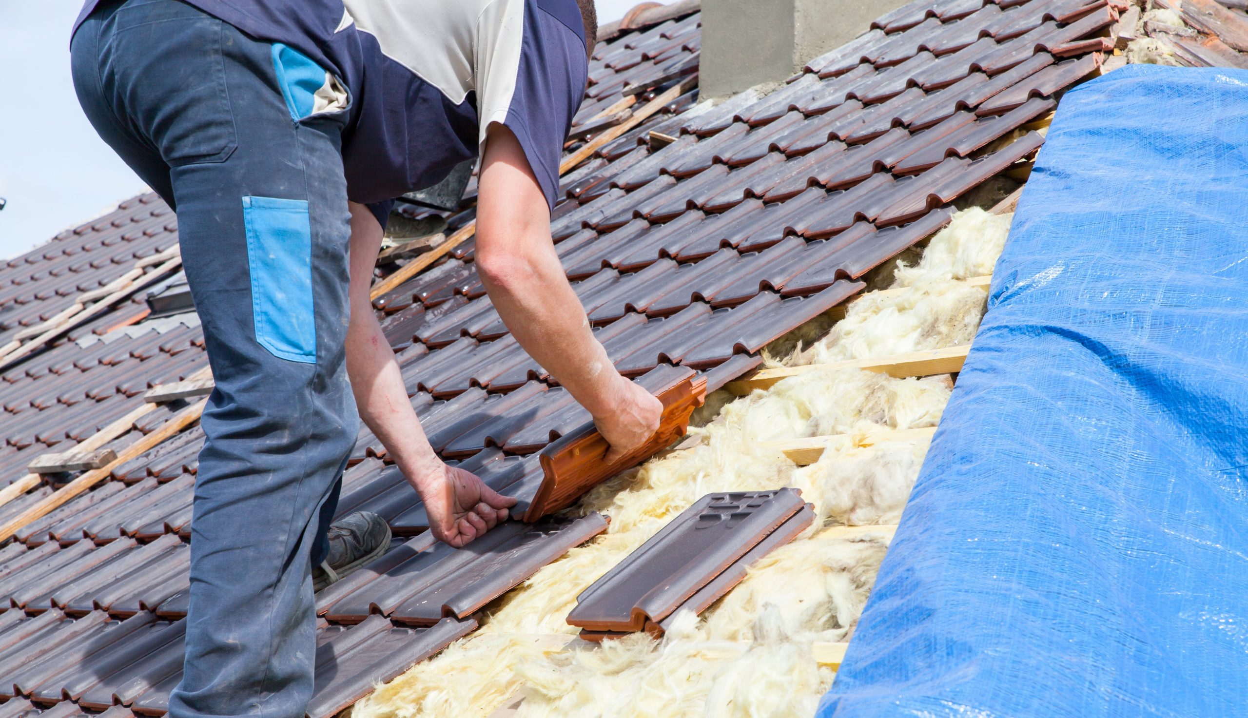 a roofer laying tile on the roof