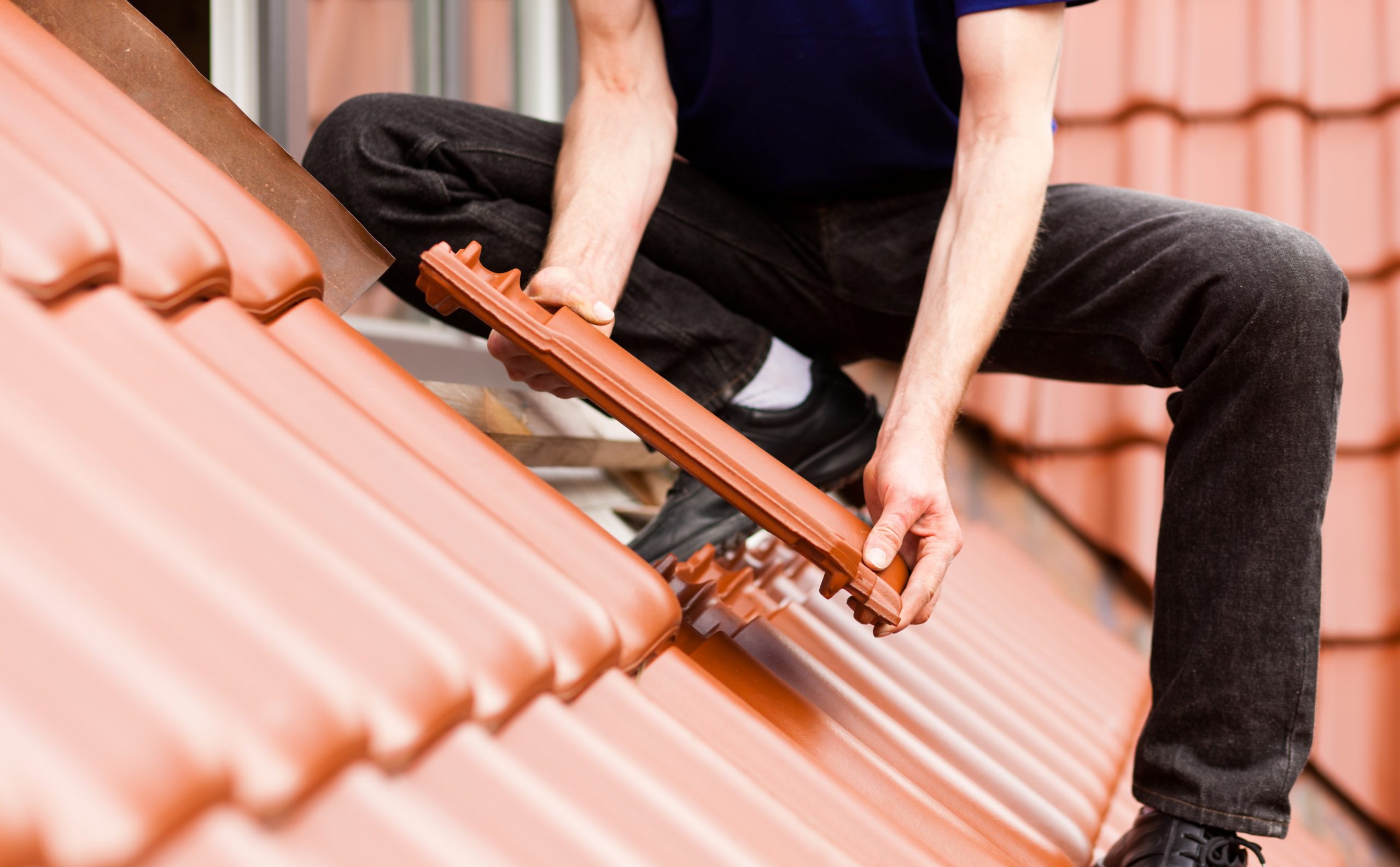 Roofing - construction worker standing on a roof covering it with tiles